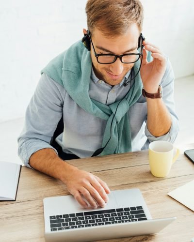 Call center operator talking on headset and using laptop